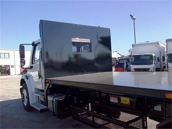 Truck body showing a flatbed with a tall black partition box behind the cab, side view, white cab, with steel mesh compartments and underbody equipment.