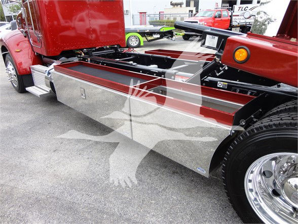 Peterbilt 337 chassis side view showing chrome fuel tank cover and wheel with tread. Red cab, metal side panel, flatbed area and visible tires.