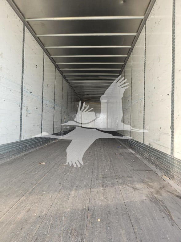 Truck trailer interior empty cargo space with white walls and ribbed ceiling panels, no visible equipment or text.