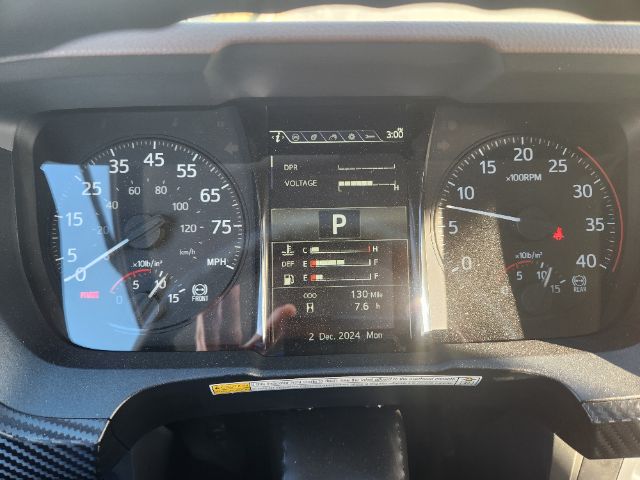 Vehicle dashboard with multiple digital displays. Left gauge shows speedometer with mph and km/h, right gauge shows tachometer. Center panel displays gear 'P', various indicators, date '2 Dec, 2024 Mon'.