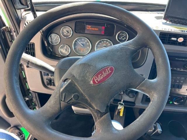 Peterbilt truck dashboard with steering wheel. Visible text on gauge cluster and warning message on small screen. Peterbilt logo on steering wheel.