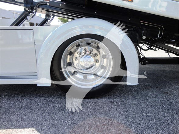 Wheel/tire and part of truck with chrome rim and white body, tow truck category, 2022 Hino 268A in-service.