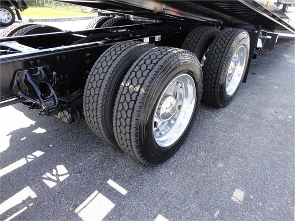 Kenworth W990 tractor trailer rear wheels and dual axle with dual tires, chrome rims, undercarriage frame and suspension visible.