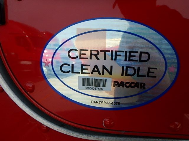 Certified Clean Idle badge on the rear of a red Peterbilt truck door with barcode and PACCAR logo.