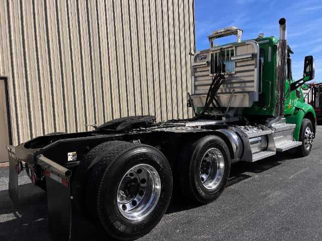 2018 Peterbilt 579 conventional daycab tractor from rear three-quarter view showing green cab, dual rear axles, and flatbed/undercarriage area.