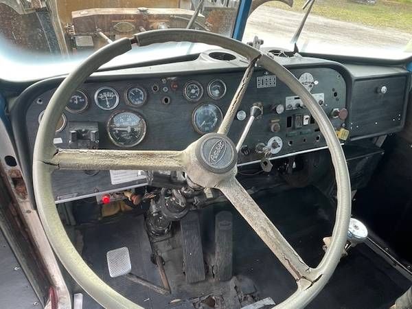 Peterbilt truck interior showing steering wheel and dashboard with analog gauges and old controls.