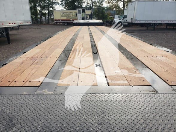 XL Specialized Xl80Sa trailer bed showing wooden deck and diamond plate edges with fleet in background.