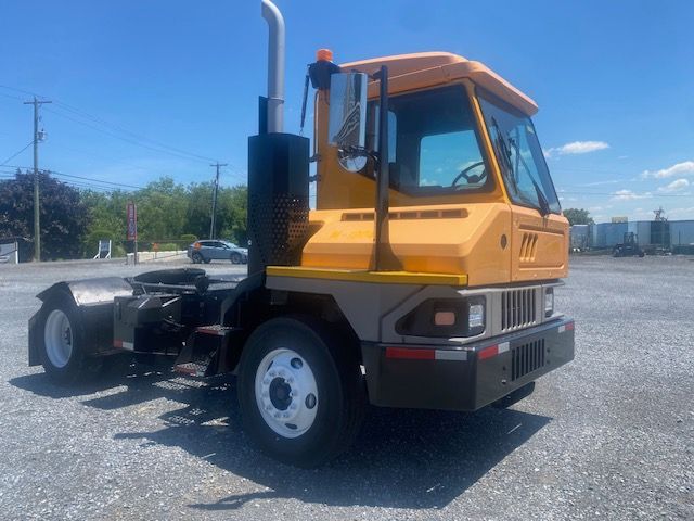 2017 Ottawa T2 yard truck side view showing cab, exhaust stack, and front grille with orange and tan color scheme.