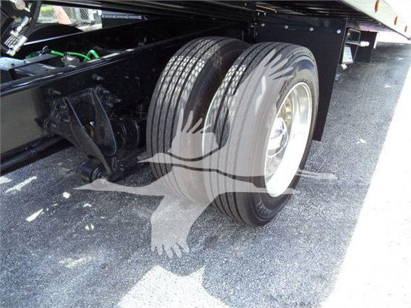Trailer truck axle with dual rear wheels and visible suspension components.