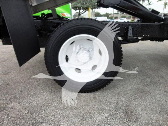 Isuzu NQR truck chassis showing white steel wheel and tire, with dump body framework in background.