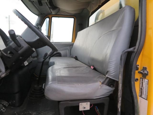 Interior of a 2005 International 4200 VT365 truck cab showing gray bench seat and steering wheel, manual gear shifter, and door with yellow exterior.