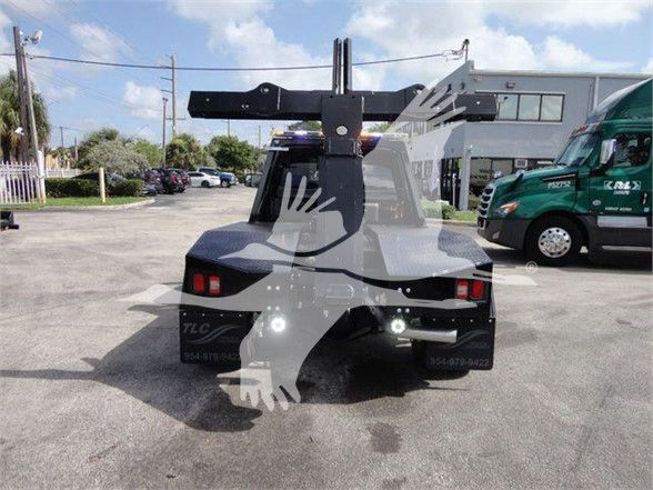 Ram 4500 tow truck rear view with hitch and hoist mounting, visible tail lights and surrounding lot.