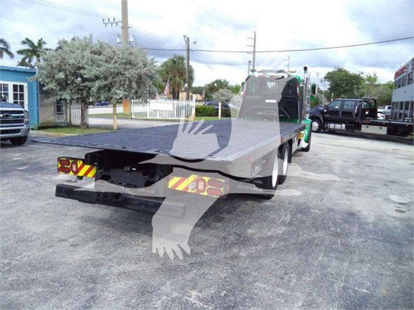 Tow truck flatbed rear view showing aluminum flatbed and rear taillights with reflective chevrons.