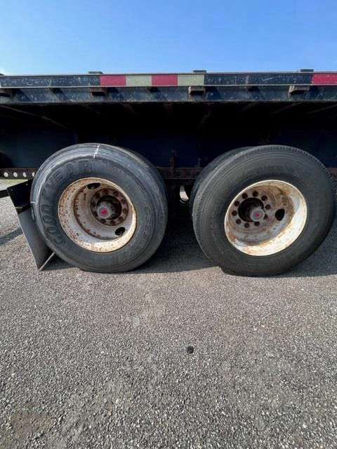 Manac flatbed trailer wheels and undercarriage showing dual rear tires and wheel hubs.