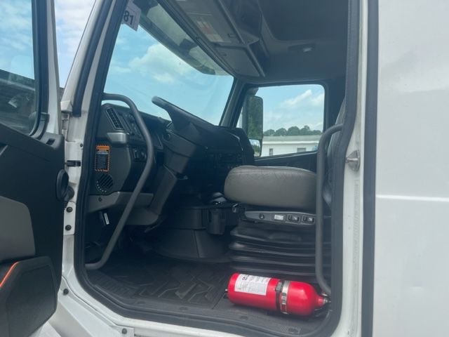 Volvo VNL64T740 cabin interior showing steering wheel, driver's seat, and a red fire extinguisher on the floor near the door.