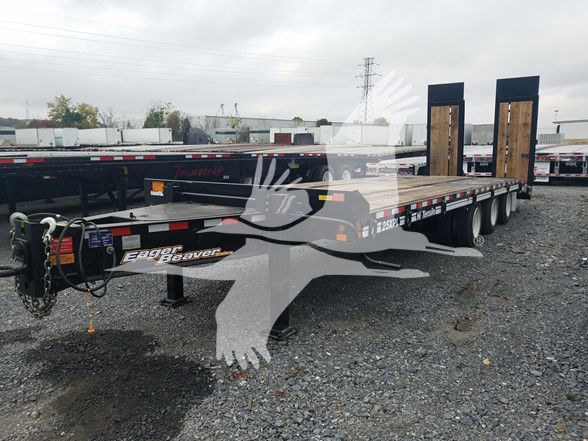 Trailer deck with dual flatbed sections and tall ramps; brand 'Eager Beaver' visible on front tongue and side rails; black frame, triple-axle setup, wooden deck ramps.