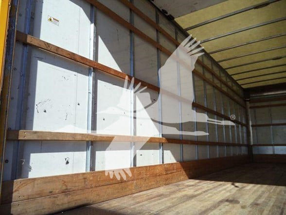 No engine bay or labels visible in this image. Interior of a large empty truck trailer with wooden floor and metal side walls.
