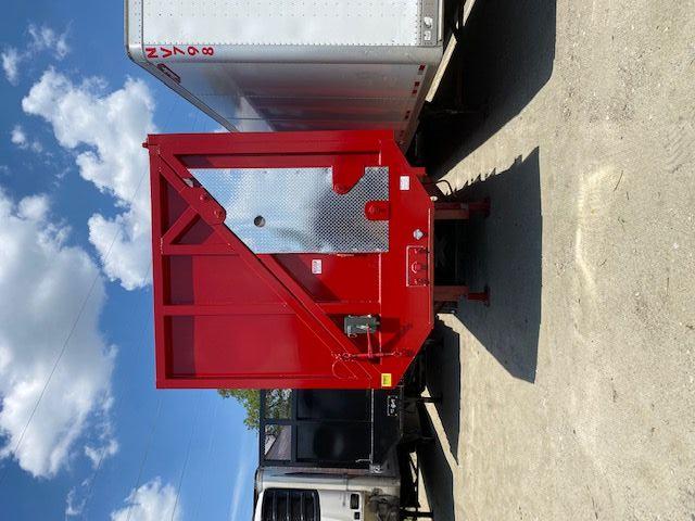 Red Transcraft 48 ft trailer with diamond plate panel on side, rear door with diagonal brace, standing on a support legs.