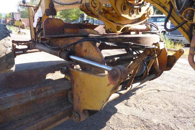 Caterpillar 16G grader front hitch and hydraulic linkage with yellow paint and metal arms.