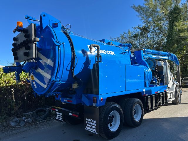 Blue Sterling vacuum truck with large circular rear intake, multiple axles, and hoses; side text includes 'VAC-CON' and various labels on the rear bumper.