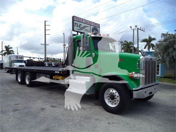 2014 Peterbilt 367 tow truck with green cab and white bumper, flatbed tow body, front grille, and large dual rear wheels visible.
