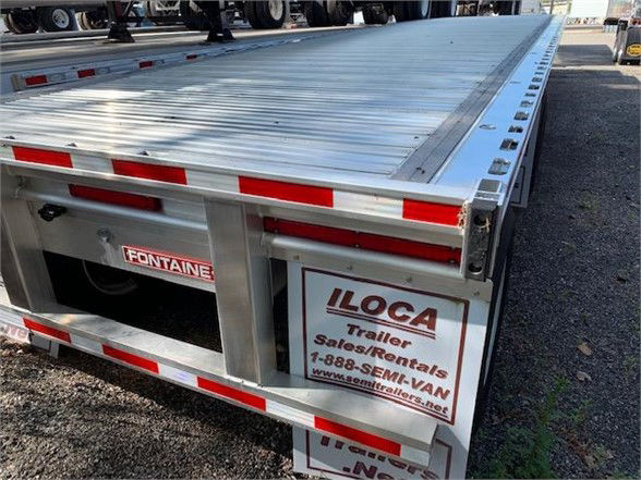 Flatbed trailer rear showing Fontaine aluminum plate and ILoca rental sign