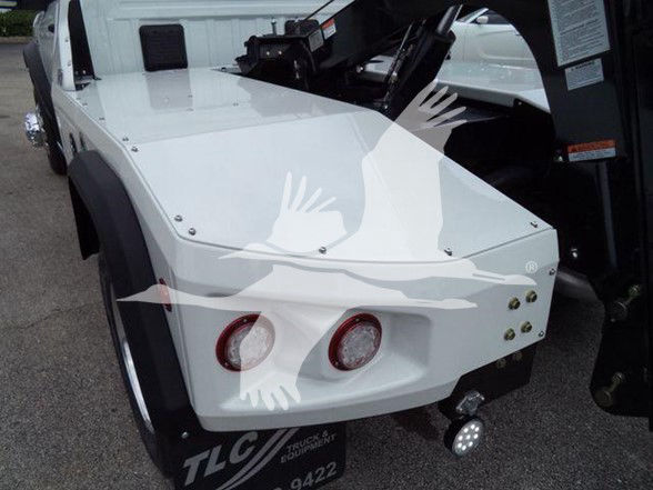 Ram 4500 tow truck rear corner showing white body panels and tow hitch with circular tail lights and brackets.