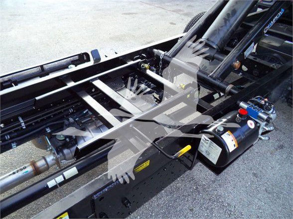 Isuzu NPR HD truck chassis with hydraulic tank and control valve visible, frame rails and components, with visible labels and hoses.