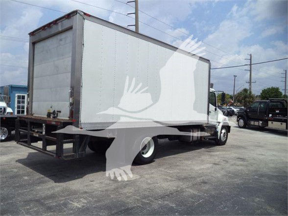 Rear and side view of a white box truck with a silver cargo box and black undercarriage in a lot.