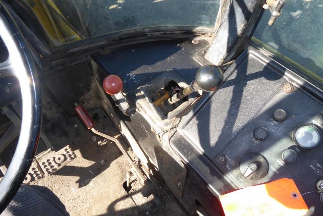 John Deere 710B cab interior showing two joystick levers (red and black) and control panel with gauges and pedals.