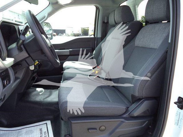 Interior of a 2024 Ford F-450 front seats and dashboard view from the driver side, cloth seats, steering wheel visible, passenger seat, clean cabin.