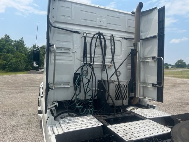 Truck cab rear view showing hoses and connectors mounted on back of sleeper area, Volvo VNL storage and exhaust stack visible.