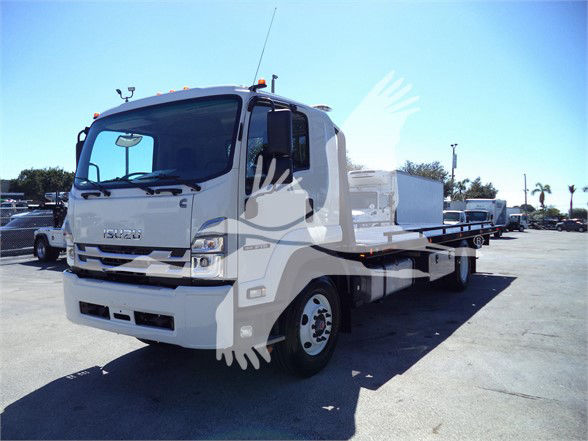 Isuzu FTR tow truck with flatbed in a parking lot.