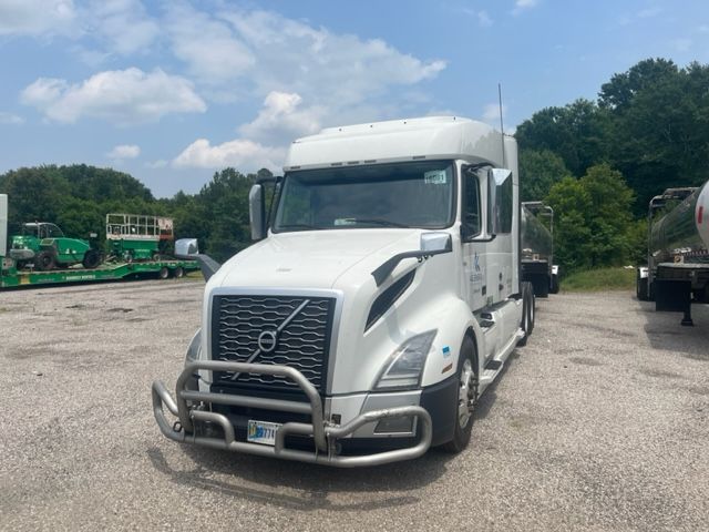 Volvo VNL64T740 sleeper cab truck in a gravel lot with a bull bar and chrome grille guard.