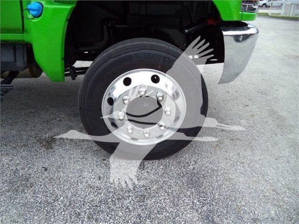 Truck front wheel and green fender with chrome hub and lug nuts; partial view of front bumper and fender flare.