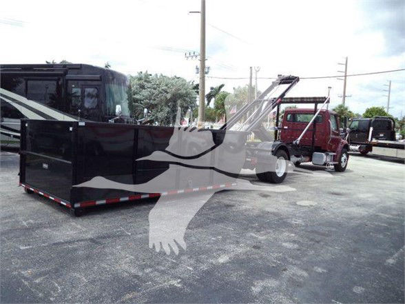 Freightliner BUSINESS CLASS M2 106 truck in lot showing a black dump body with a hydraulic crane attachment and red trucks in background.