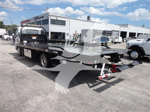 Isuzu NRR tow truck with flatbed and rear hydraulic tilt, stock number NRRDSL22XLP visible in a dealership lot.