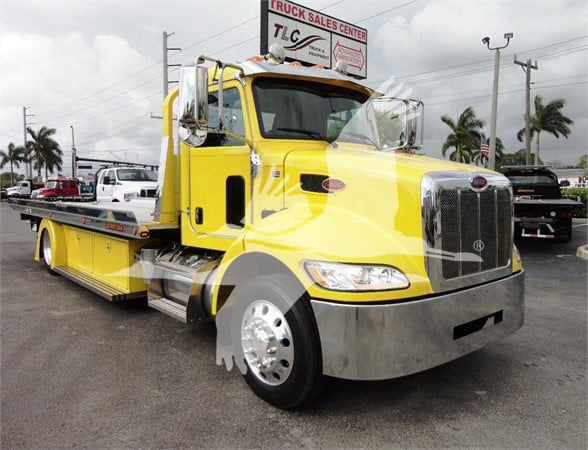 Peterbilt 337 tow truck in yellow with chrome grille and flatbed, front-right view showing cab and bumper.