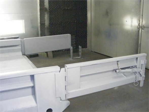 Truck body trailer hitch and 14 ft dump body steel sides in a workshop setting, showing rear extension and safety chains.