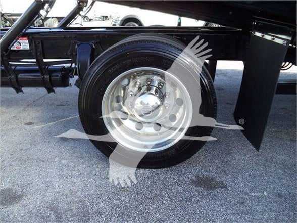Freightliner Business Class M2 106 Plus wheel and tire assembly under trailer frame showing polished steel wheel and black fender.