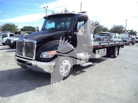 Kenworth T280 tow truck chassis with flatbed, black cab, side steps, front chrome grille, large mirrors.