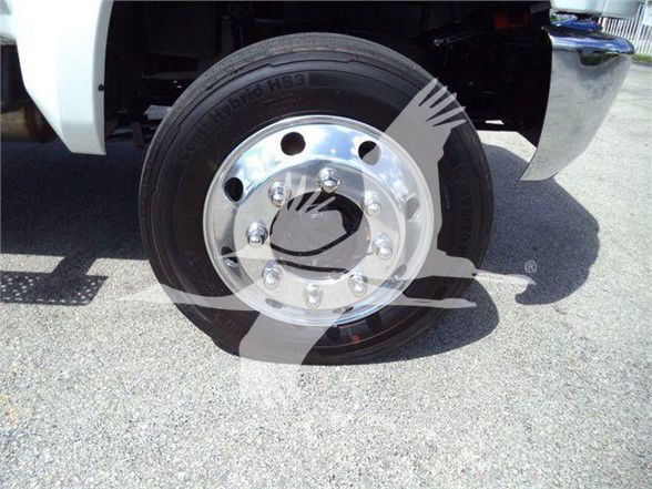 Wheel and tire on a white truck fender showing chrome hub and lug nuts; faint text on tire reading 'Duel... 16R22.5' or similar. No additional labels visible.