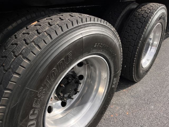 Truck wheels and tires of a Freightliner Cascadia 125 dump truck showing Goodyear tires and polished aluminum rims.