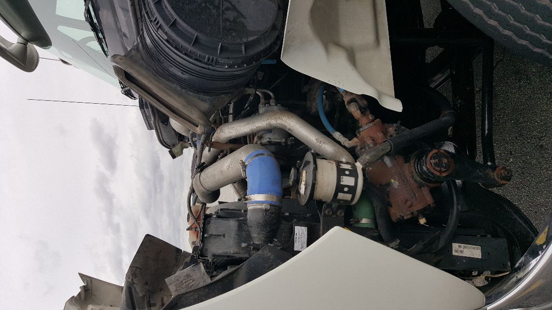 Truck engine bay with exposed components, blue hose, silver pipes, and air intake duct visible on a 2007 International 8600 cab.