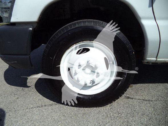 Wheel and tire of a Ford E-450 truck with white steel rim in front fender area.