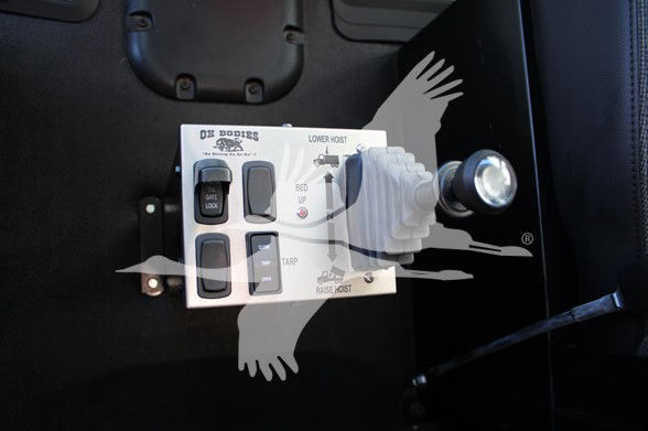 Control panel with labeled switches and levers mounted on a black surface; appears to be a truck control console with buttons and a knob.