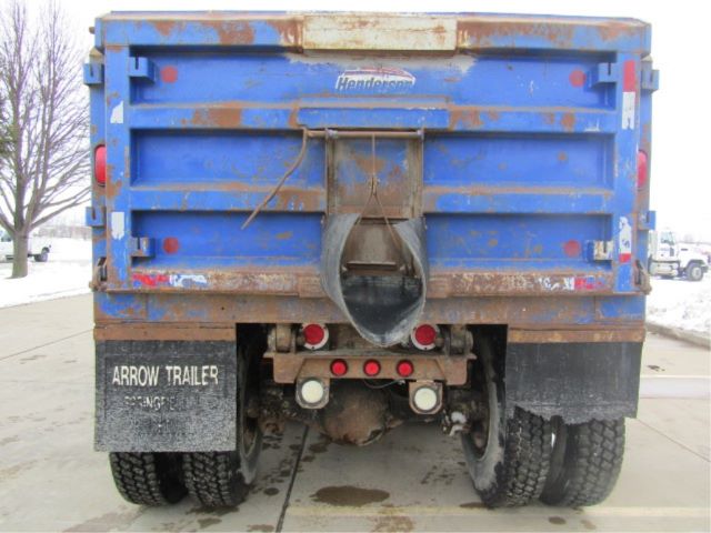 Rear view of a blue Sterling LT8500 dump truck with rust and wear on the bed, arrow trailer mud flaps, and a round tow hitch opening.