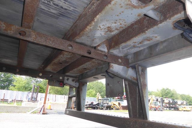 Trailer frame underside with rusted steel beams and structural supports.