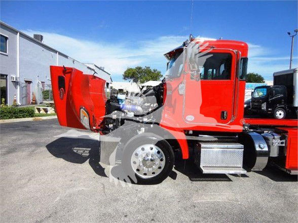 Peterbilt 337 truck in red with hood open showing engine bay and front wheel area.