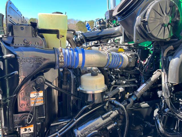 Truck engine bay with blue silicone hose couplings and green chassis, hydraulic reservoir, and various hoses and components visible.